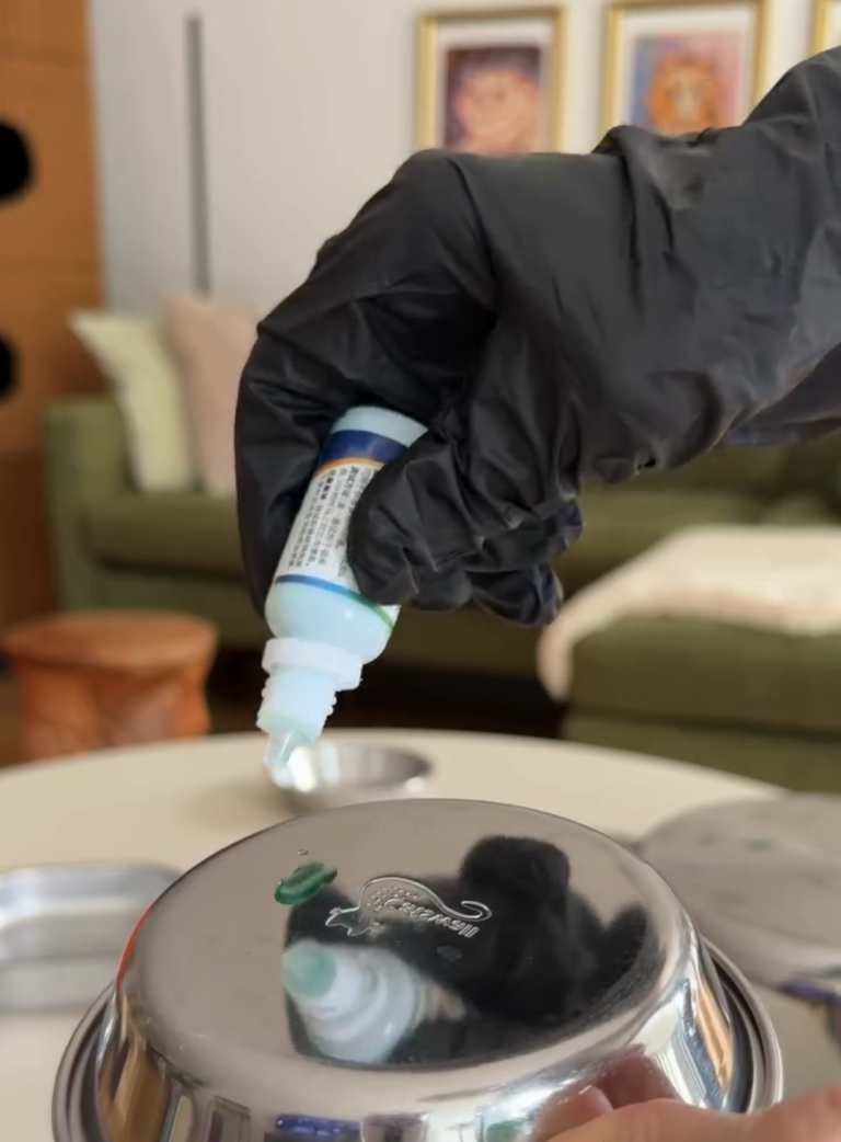 Testing a stainless steel cat food bowl for heavy metal purity using a blue chemical drop test on the metal surface.